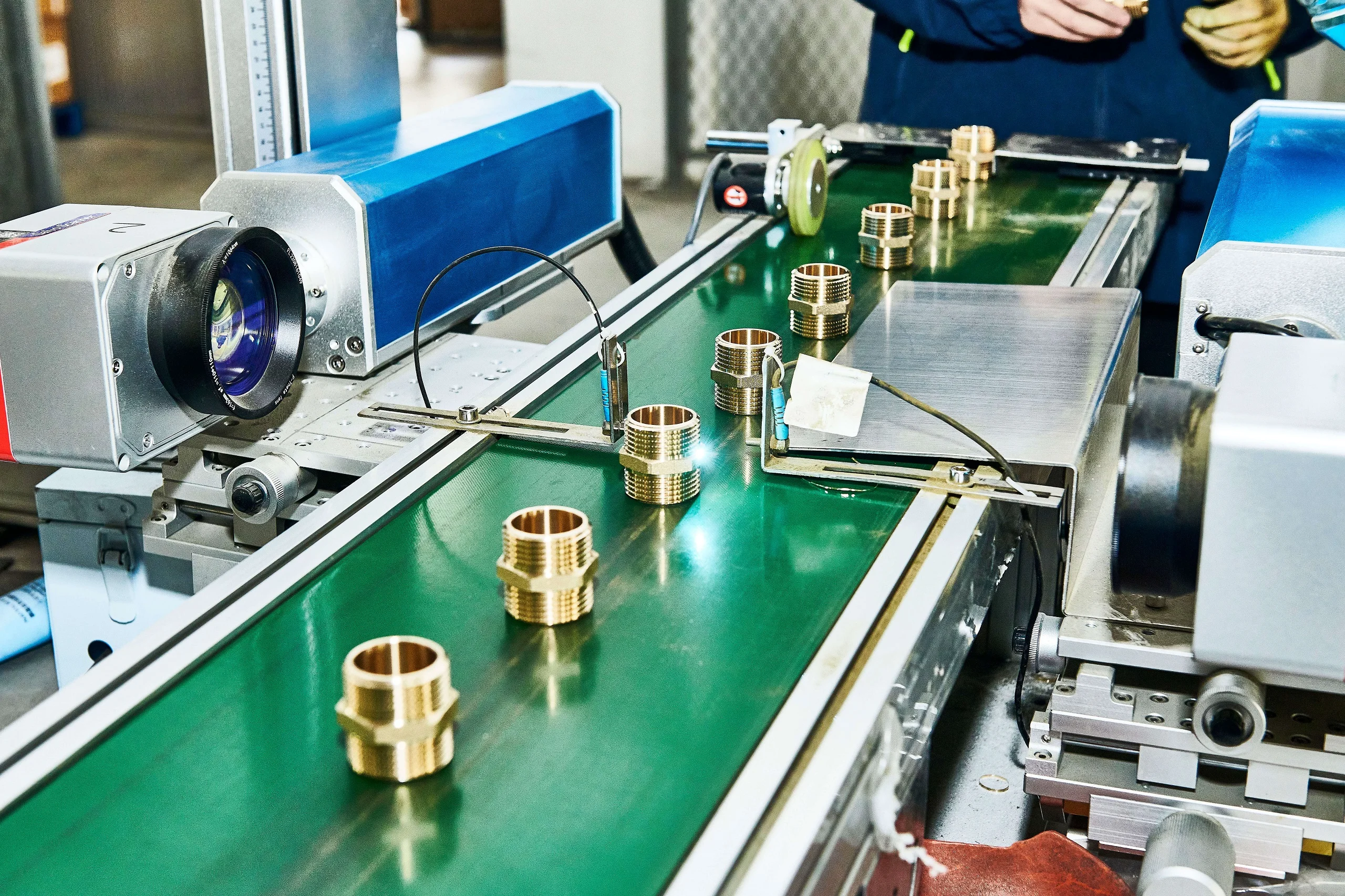 Finished white PPR pipe fittings with brass inserts visible at the threaded connection points, freshly ejected from the mold